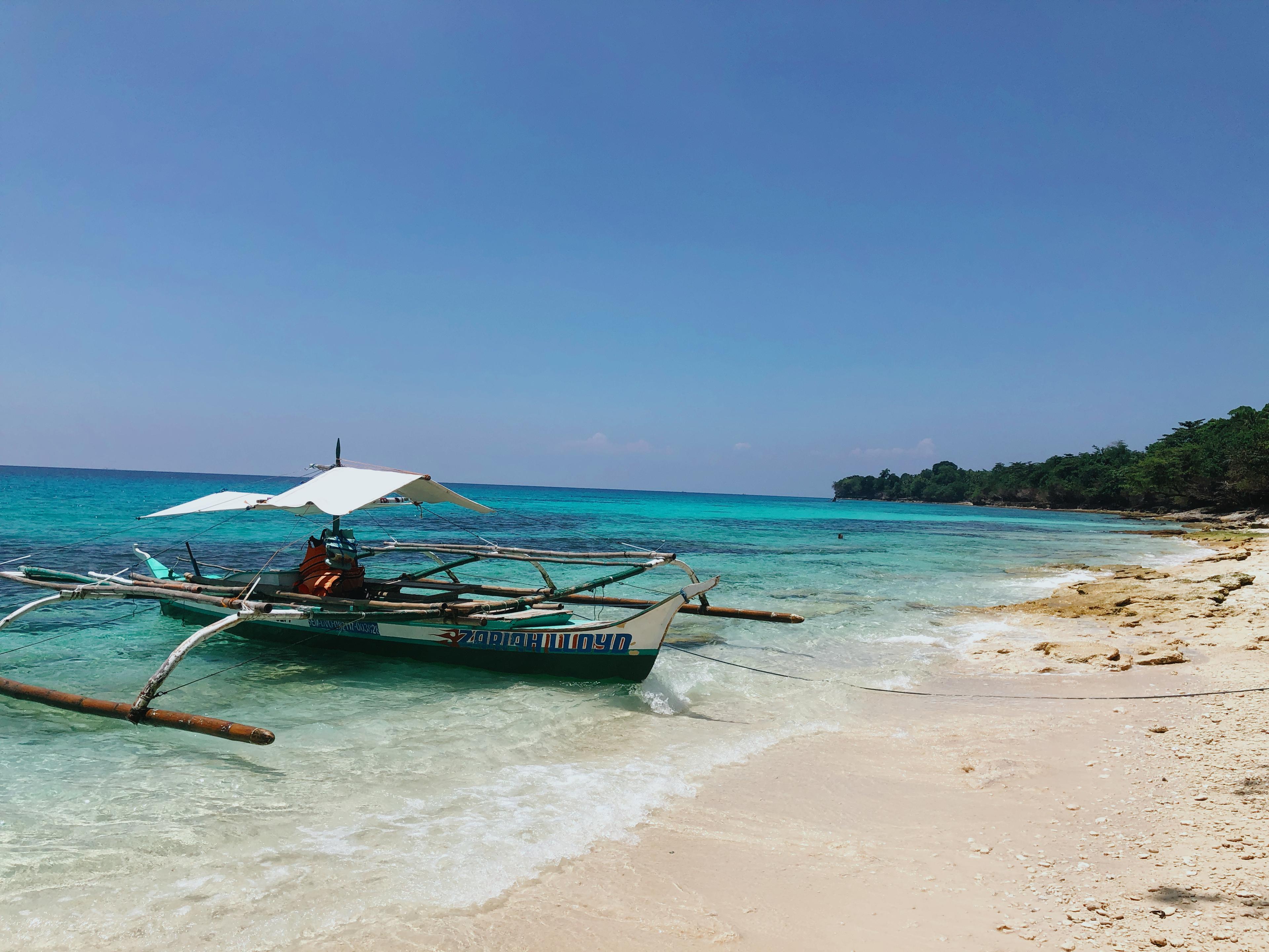 An outrigger boat beside a tropical Philippine shore